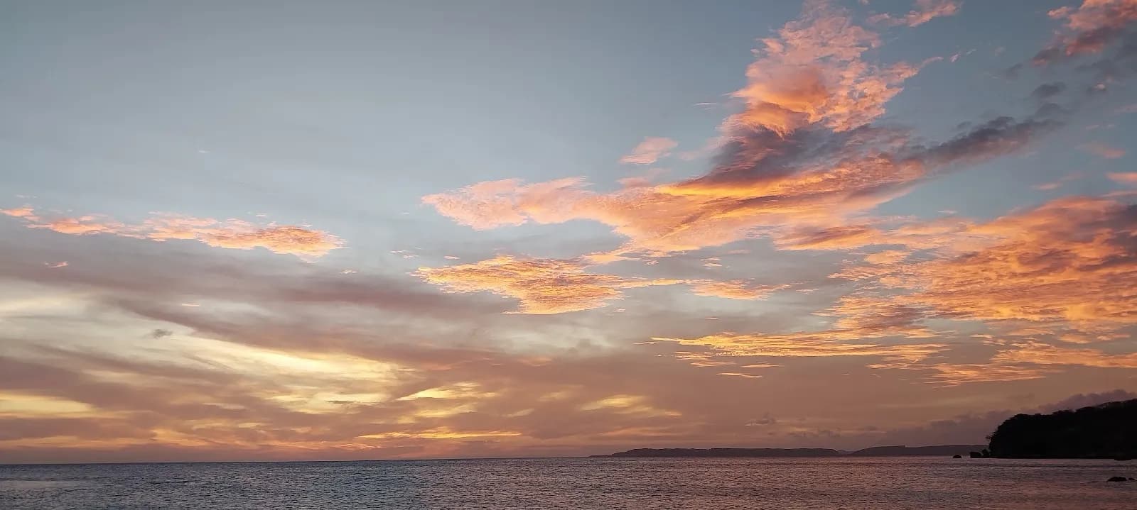 Avondlucht met roze en oranje wolken boven een open landschap