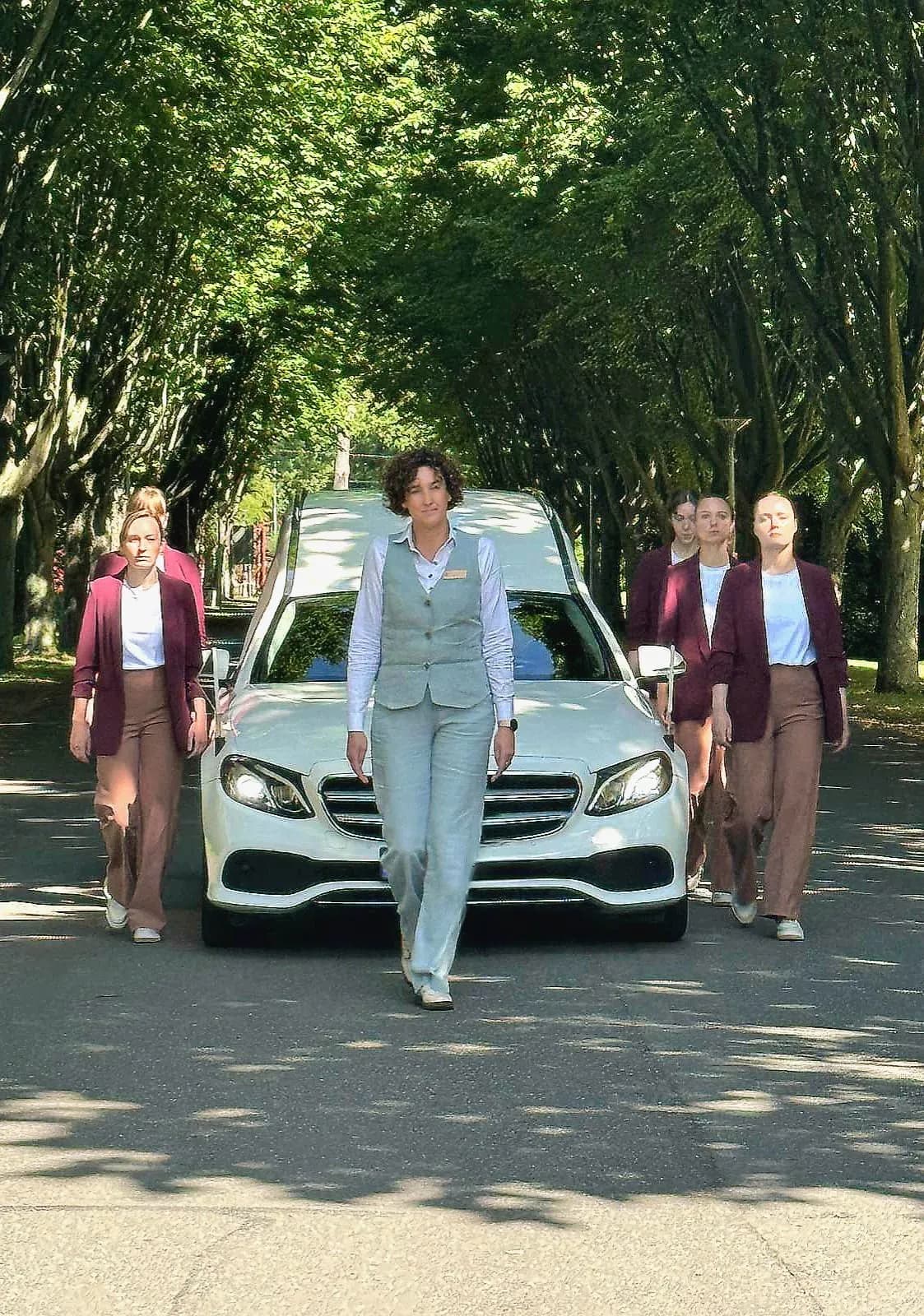 Voorlopen voor de rouwauto, met naasten aan weerszijden
